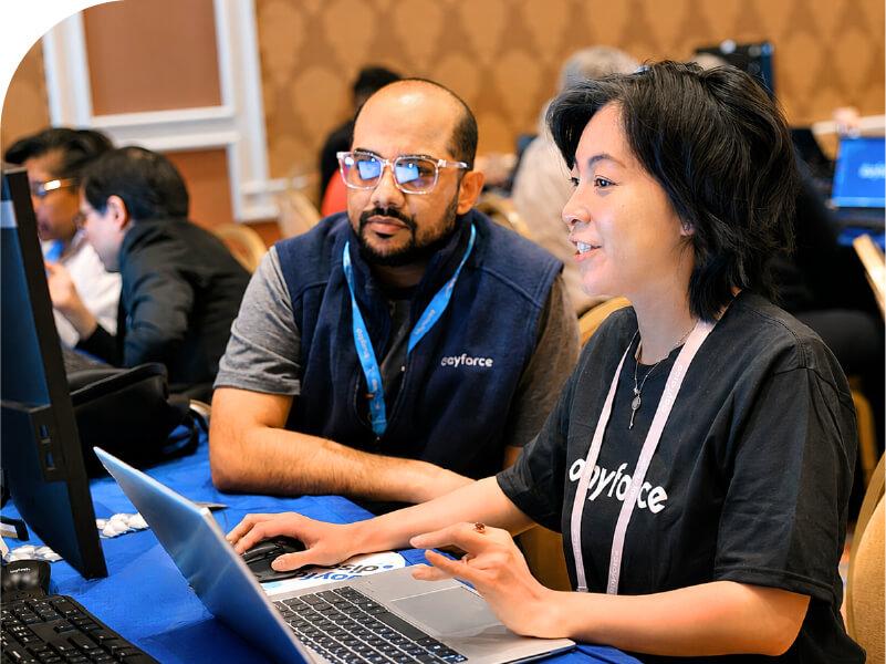 An attendee learning from a Dayforce staff member at a laptop during a FIT session